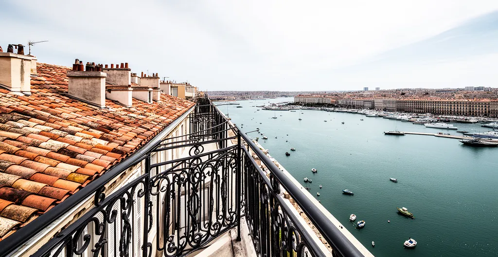 Vue aérienne d'un appartement marseillais avec terrasse donnant sur le Vieux-Port, sous un ciel bleu méditerranéen