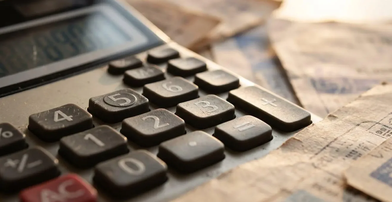 Gros plan sur une calculatrice et des factures de charges immobilières