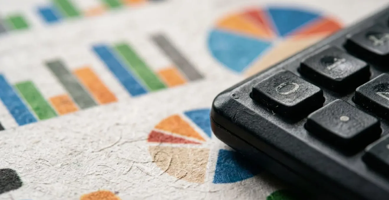 Calculatrice posée sur des documents financiers avec graphiques montrant une courbe ascendante